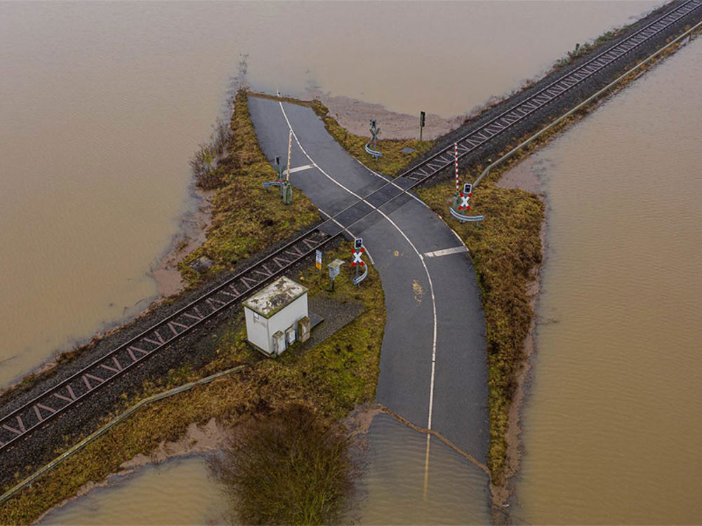 Aerial view of a flooded road and railway crossing the road