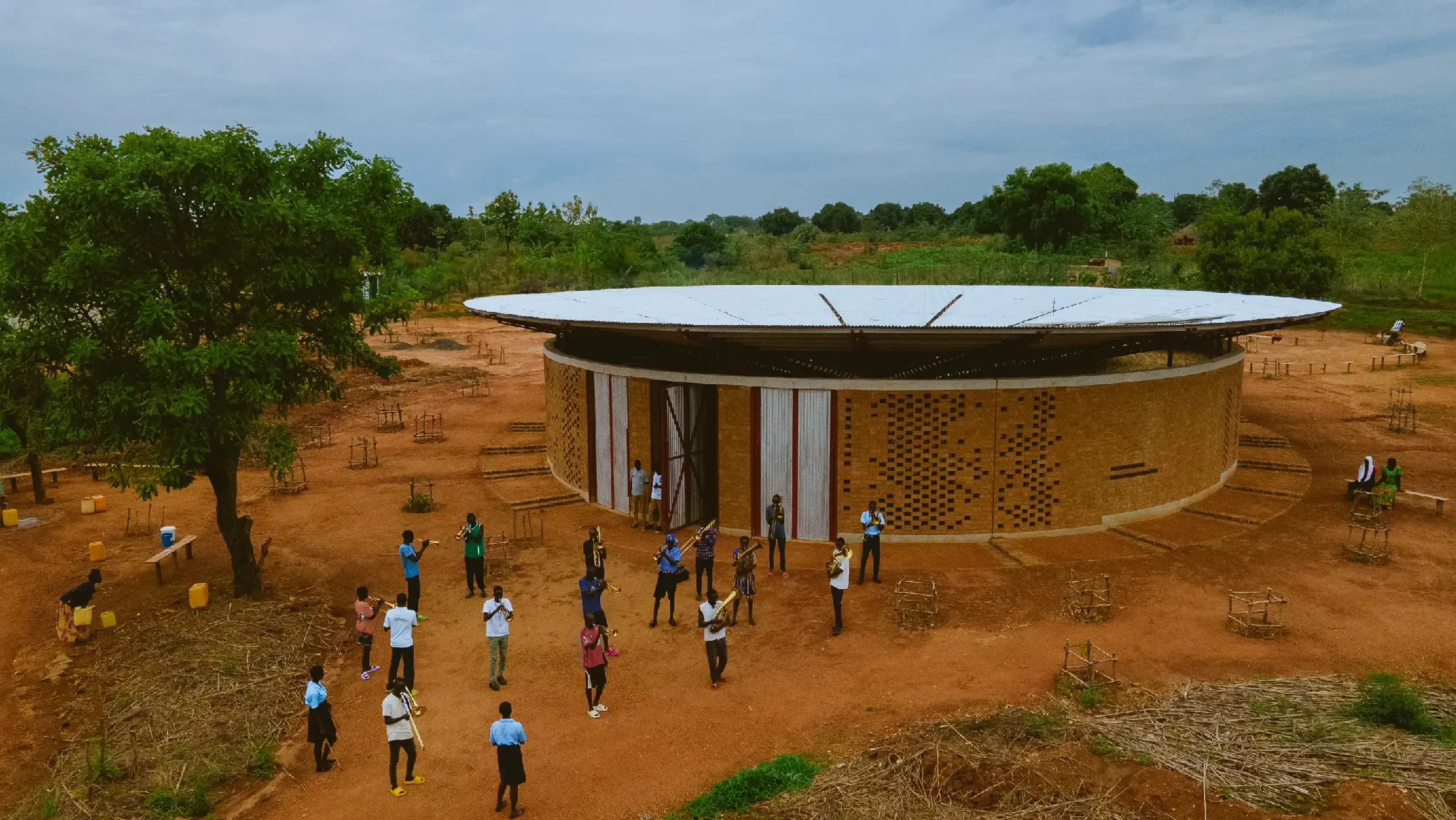 People outside Bidi Bidi Arts Centre in Northern Uganda, surrounded by trees and blue skies