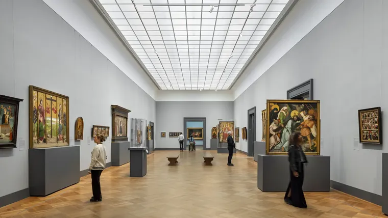 People viewing artwork in a museum gallery with a large skylight above
